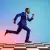 A man in a blue suit running energetically across a black-and-white checkered floor, against a vibrant gradient background of pink, purple, and blue.
