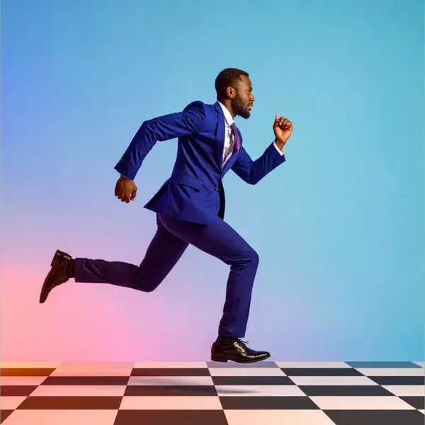 A man in a blue suit running energetically across a black-and-white checkered floor, against a vibrant gradient background of pink, purple, and blue.
