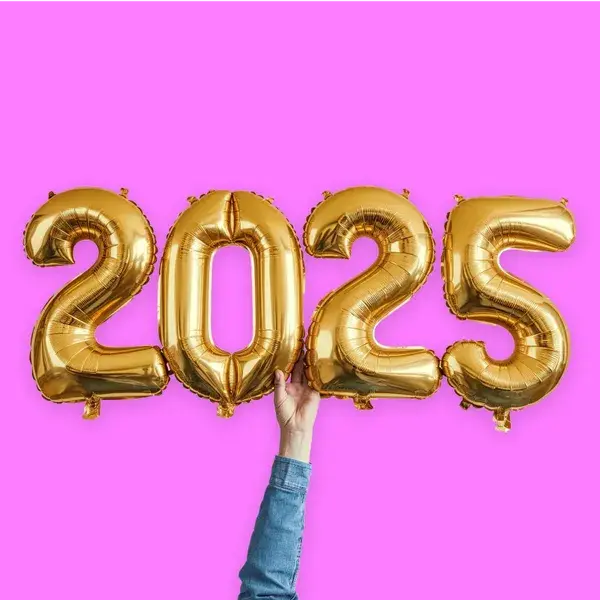 Gold 2025 balloons held up by a hand against a bright pink background